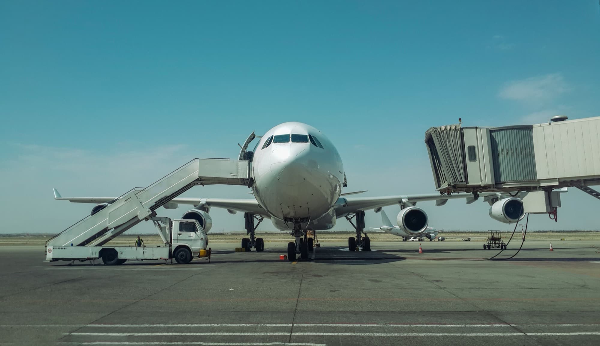 Un avión estacionado en una puerta del aeropuerto con la manga de embarque conectada
