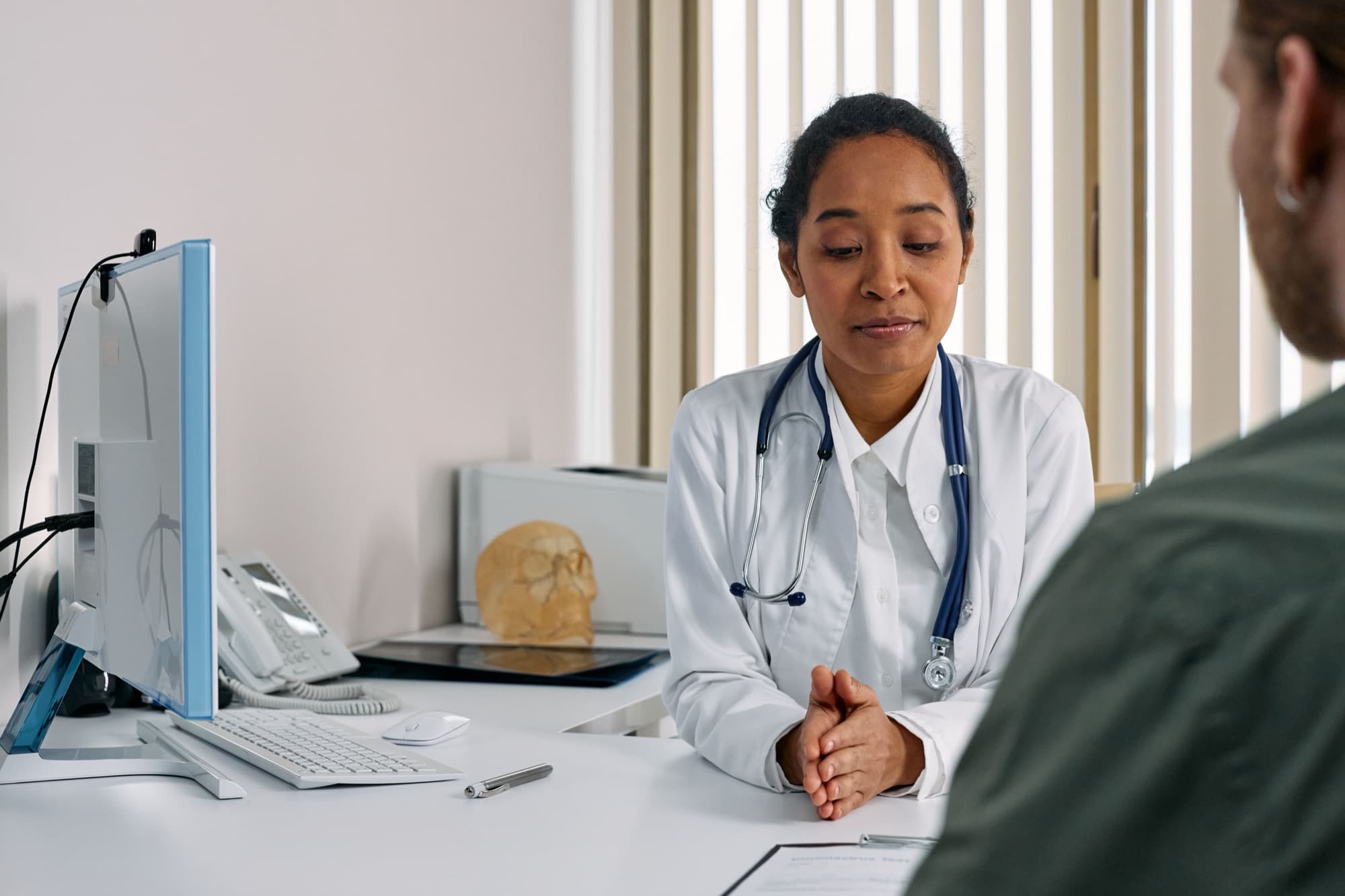 A physician in consultation with a patient across a desk