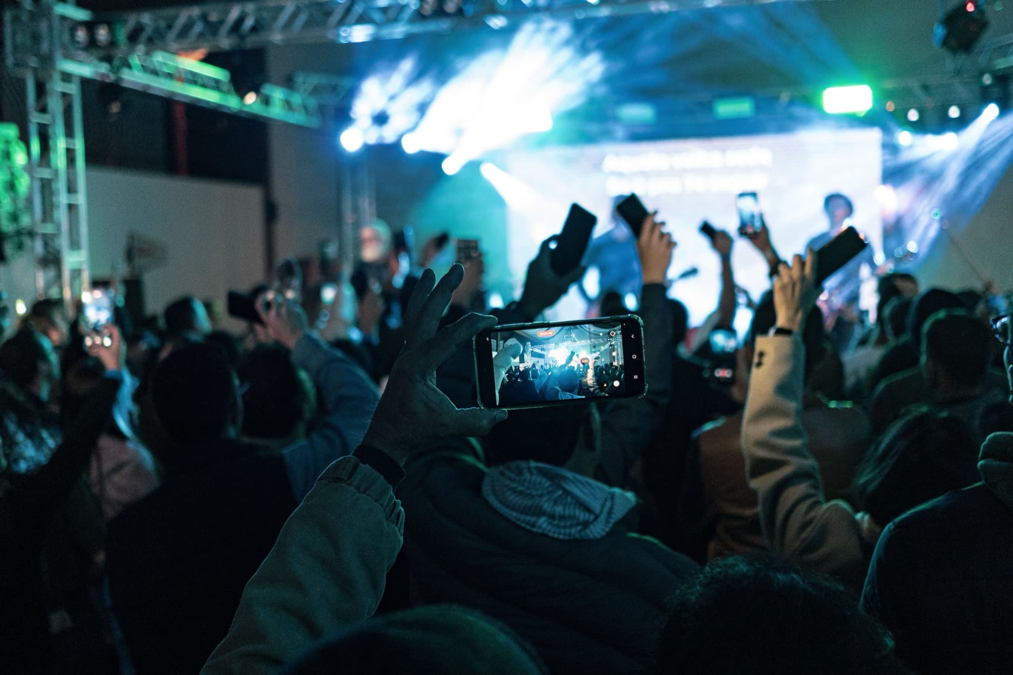 A large crowd at a night-time event in front of a lit stage