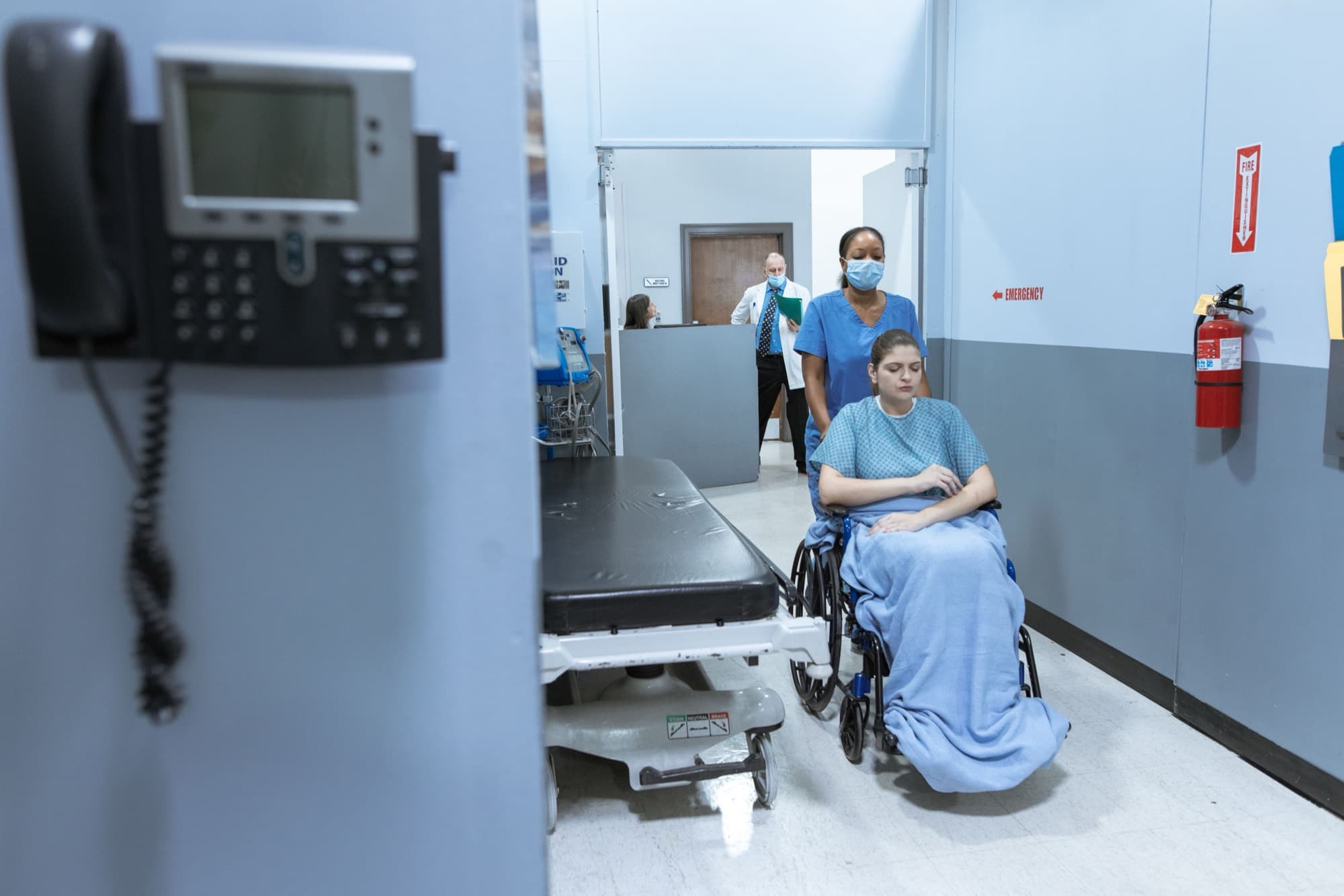A patient being taken through a hospital corridor in a wheelchair
