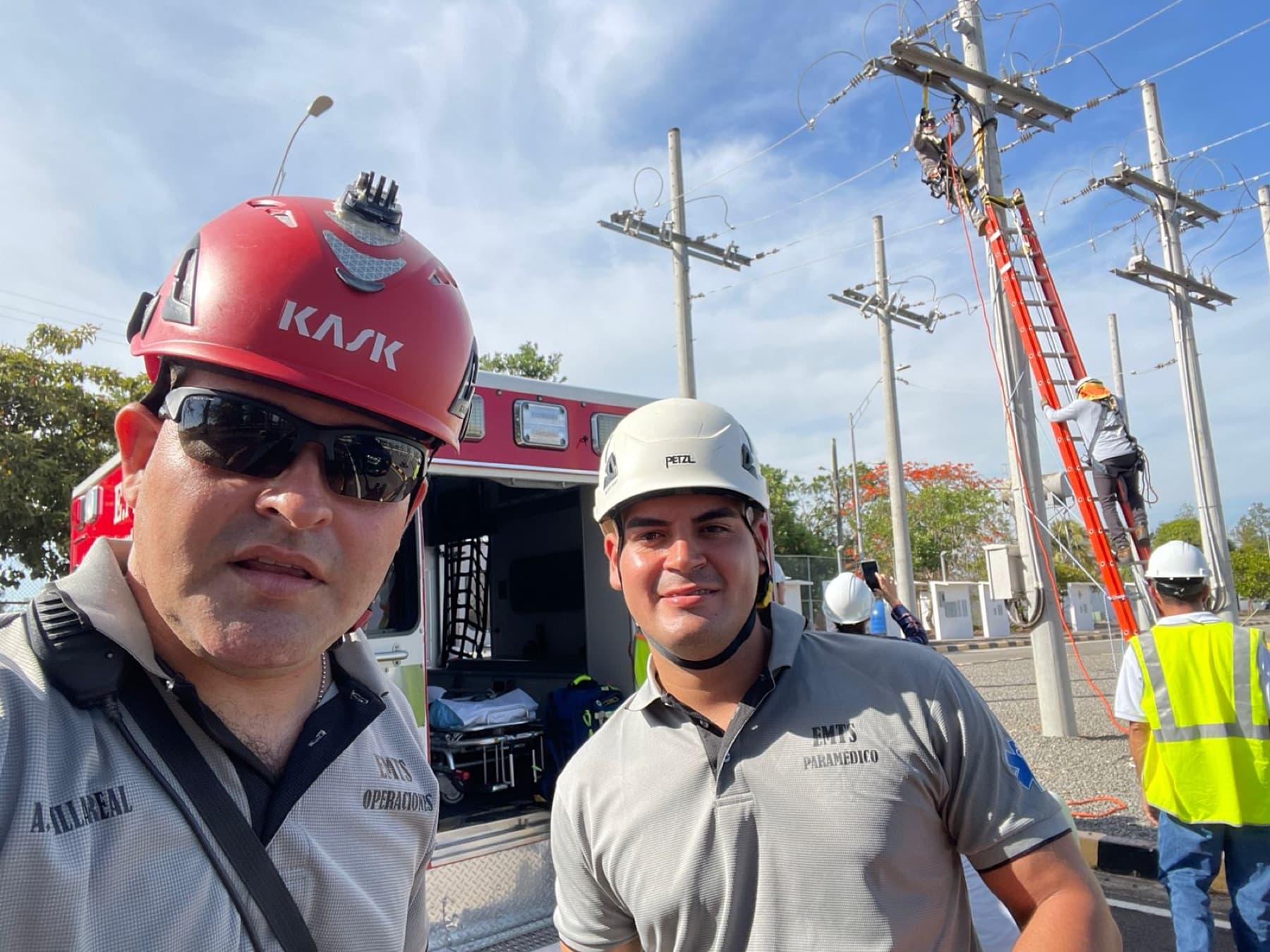 EMTS operations lead and paramedic on medical standby at a utility worksite with linemen working overhead