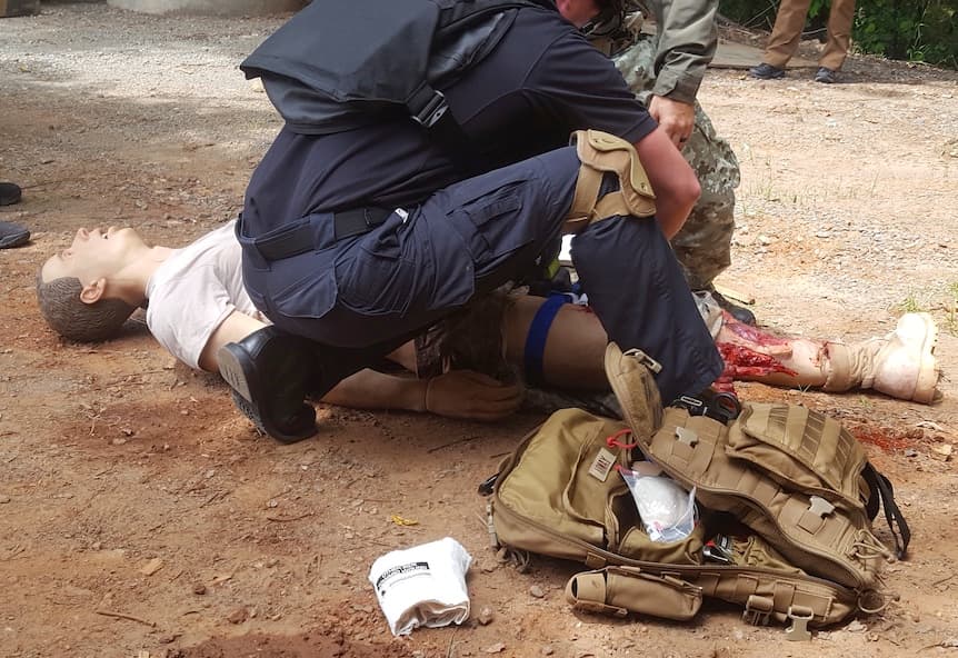 Un escenario de entrenamiento médico táctico, tratando a un herido simulado con un bolso de trauma desplegado
