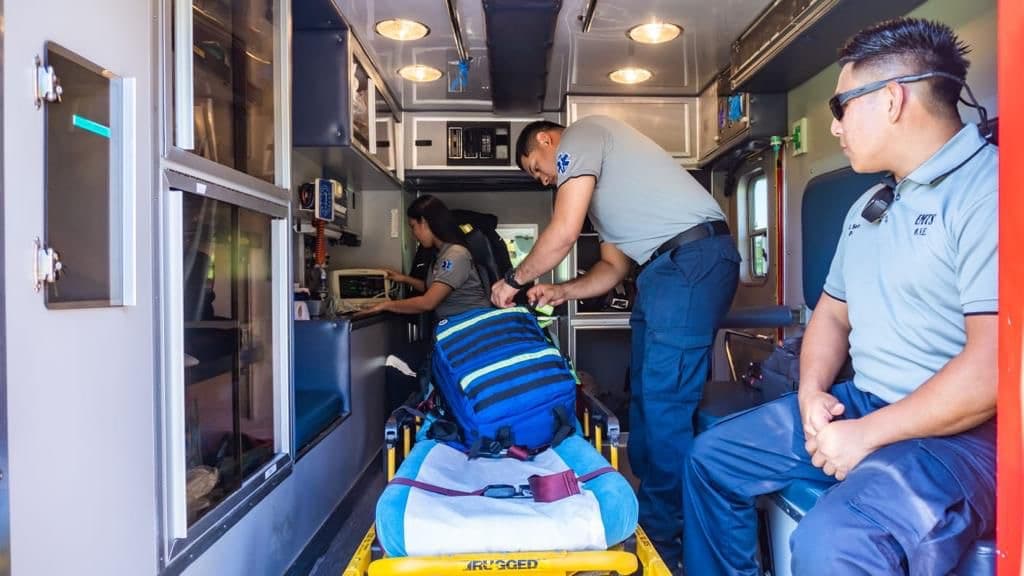Interior de una unidad de soporte vital avanzado de EMTS, con la tripulación trabajando con el monitor cardíaco